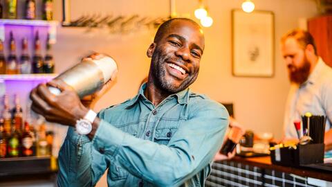 Eugene Yiga holding a cocktail shaker at a bar