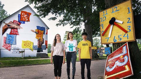 Students Dana Gentry, Jun Xue and Yangqin Yan stand in front of the Heidelberg Project, an immersive, outdoor art exhibit. 