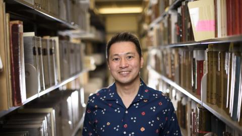 Ricky Punzalan smiling and standing in between two bookshelves. 