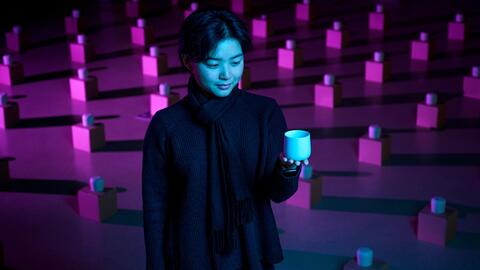 Jessie stands among tea cups laid across the floor while holding and looking at one
