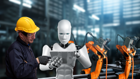 A man in safety glasses and helmet looks at a computer tablet being held by a robot. They are standing in a factory. 