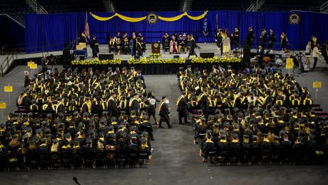 Students fill the floor of an arena for graduation