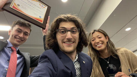 A selfie of three students posing with awards 