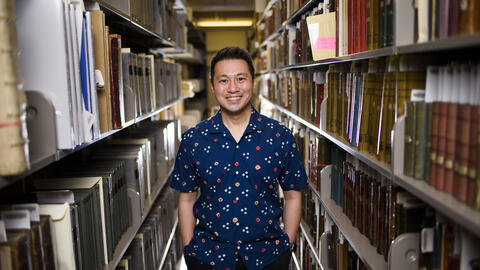 Ricky Punzalan smiling and standing in between two bookshelves. 