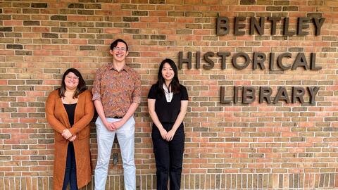 Stephanie Vettese, Clayton Zimmerman and Ziyan Zhou stand in front of the brick exterior of the Bentley, which reads "Bentley Historical Library"