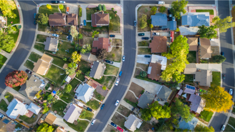 A landscape photo of a suburban neighborhood taken from above featuring a row of houses. 