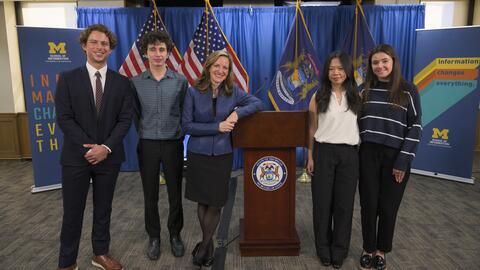 Secretary of State Jocelyn Benson poses for a photo with Jackson Gelbard, Dylan Siewert, Susan Cheng and Kathleen Andonian, standing on either side of a podium 