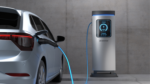 An electric car is plugged into a charging station with a blue cable, parked in front of a wall. 