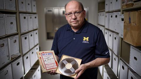 Paul Conway, a University of Michigan School of Information professor, holds a reel-to-reel tape with its matching broadcast script.