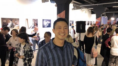 Jeff Sheng smiles at the camera in the middle of a crowded exhibition space at the 2018 Queerfest, LGBTQ festival in St. Petersburg, Russia.
