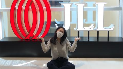 Louise Jaemin Lee sitting under a JLL sign