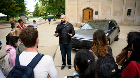 People stand around a car parked on the UM campus