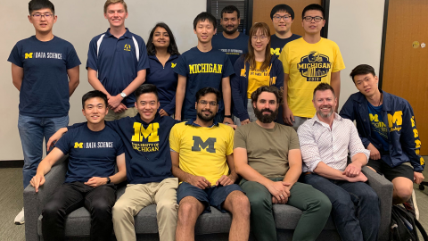 group photo of the team's tweleve members wearing maize and blue
