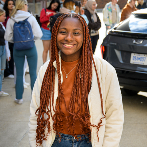 Briarre stands in front of an SUV and a group of students who are looking at it.