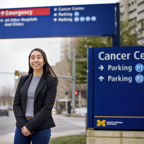 A student standing next to a sign that says "Cancer Center parking."