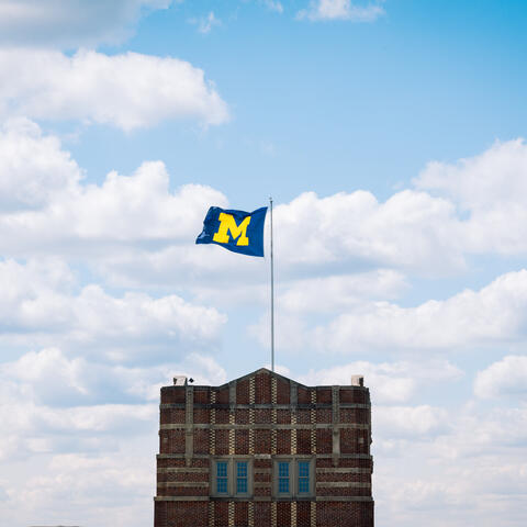The flag on top of the Michigan Union is perfectly center-framed and surrounded by fluffy white clouds on a warm summer’s afternoon.