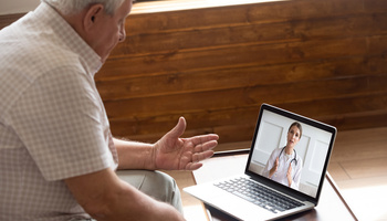 Focused older 80s patient consulting with doctor via video call. Image credit: iStock
