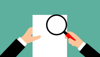 An illustration of two hands holding a piece of paper and an magnifying glass. 