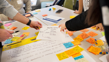Hands pointing to a flow chart on a table filled with sticky notes