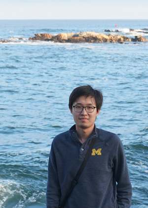 A headshot of Bohan Zhang standing in front of a large body of water