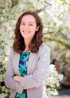 A headshot of Abigail McFee in front of flowering trees