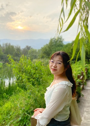 Nancy Xu standing on a path by a body of water and some greenery.
