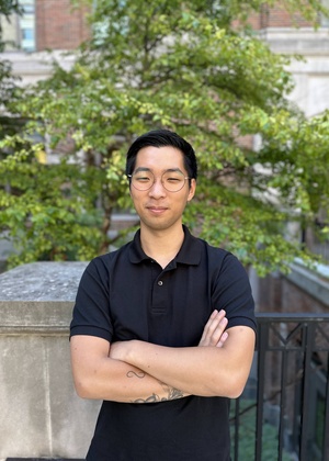 A headshot of Nathan Kim standing outside in front of a tree and a brick building.