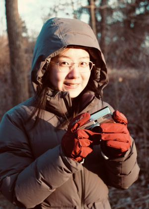 Yutong Xie wearing a parka in the woods