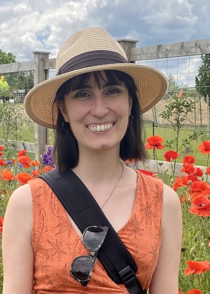 Annette Masterson standing in front of a fence and a field of poppies