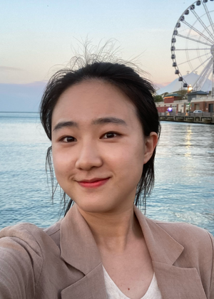 Soyoung Lee in front of a lake with a Ferris Wheel in the background.