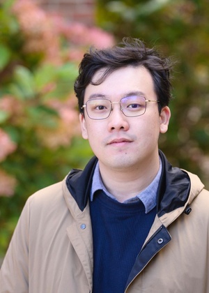 A headshot of Tong Lin in front of a flowering bush.