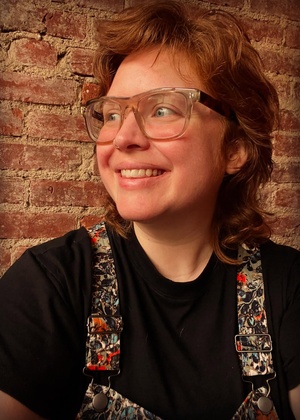 A headshot of Morgan Gray, looking off to the left in front of a brick wall.