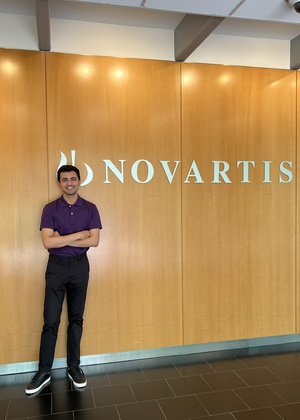 Abhishek Shah standing in front of a Novartis sign