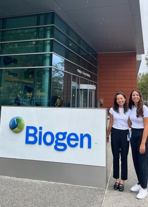 Jasmine You (left) stands with a fellow summer intern to the right of the Biogen sign outside the Biogen building.