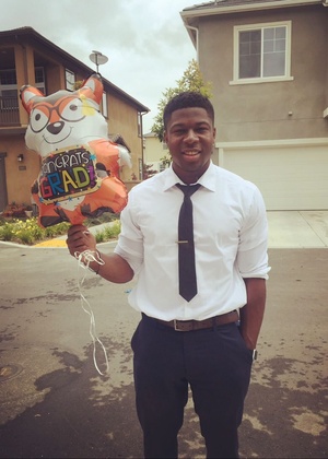 Sylvester Ikpa holding a balloon that says Congrats, grad!