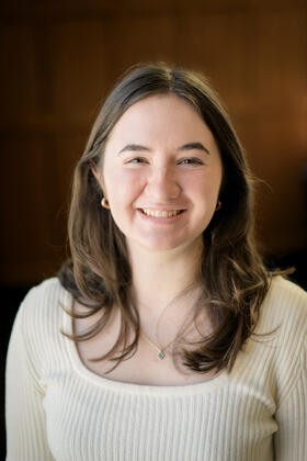 A headshot of Charlotte Parent against a warm brown background