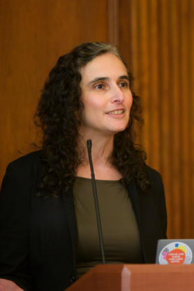 Tanya Rosenblat speaks into a microphone at a podium