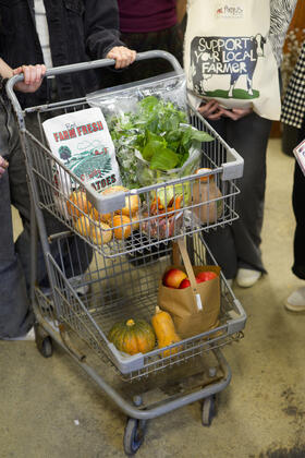 A cart filled with produce, beside a tote that says Support your local farmers