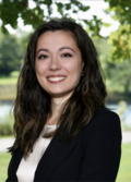 Speaker Francesca Truffa, wearing a dark jacket and white shirt with long dark hair, smiling. 