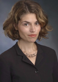 Maria Repnikova is pictured in a dark shirt, necklace with short brown hair, smiling. 