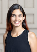 Anjalie Field, a person with dark hair with red streaks, wearing a black shirt, smiling.