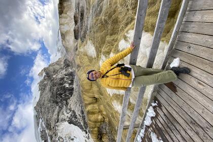 Nadiri Saunders poses in front of Mammoth Hot Springs wearing a bright yellow jacket