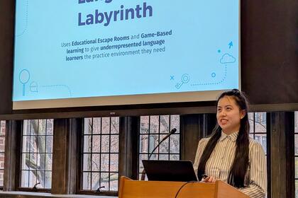 A student presents at a podium in front of a slide that reads "Language Labyrinth"