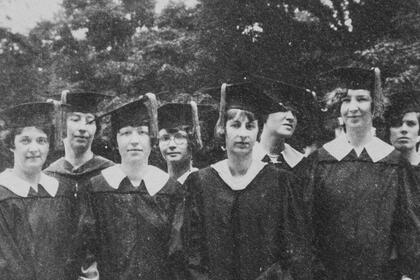 Eight students pose outside in commencement attire.