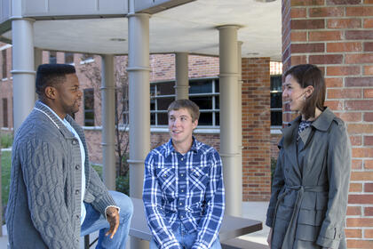 Three students outside an academic building.