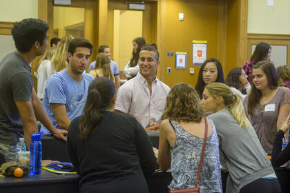 Dozens of students talking in a classroom.