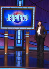 KT Lowe on a stage next to the Jeopard sign